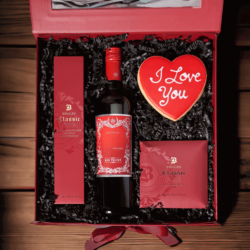The Romantic Wine Gift Box is packaged in a simple and elegant hinged gift box and filled with chocolates, a bottle of wine, and a handmade heart cookie.