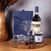 Featured in this gift there are dark chocolate truffles, blueberry preserves, a pair of wine glasses, a bottle of wine, and a beautiful end-grain cutting board.